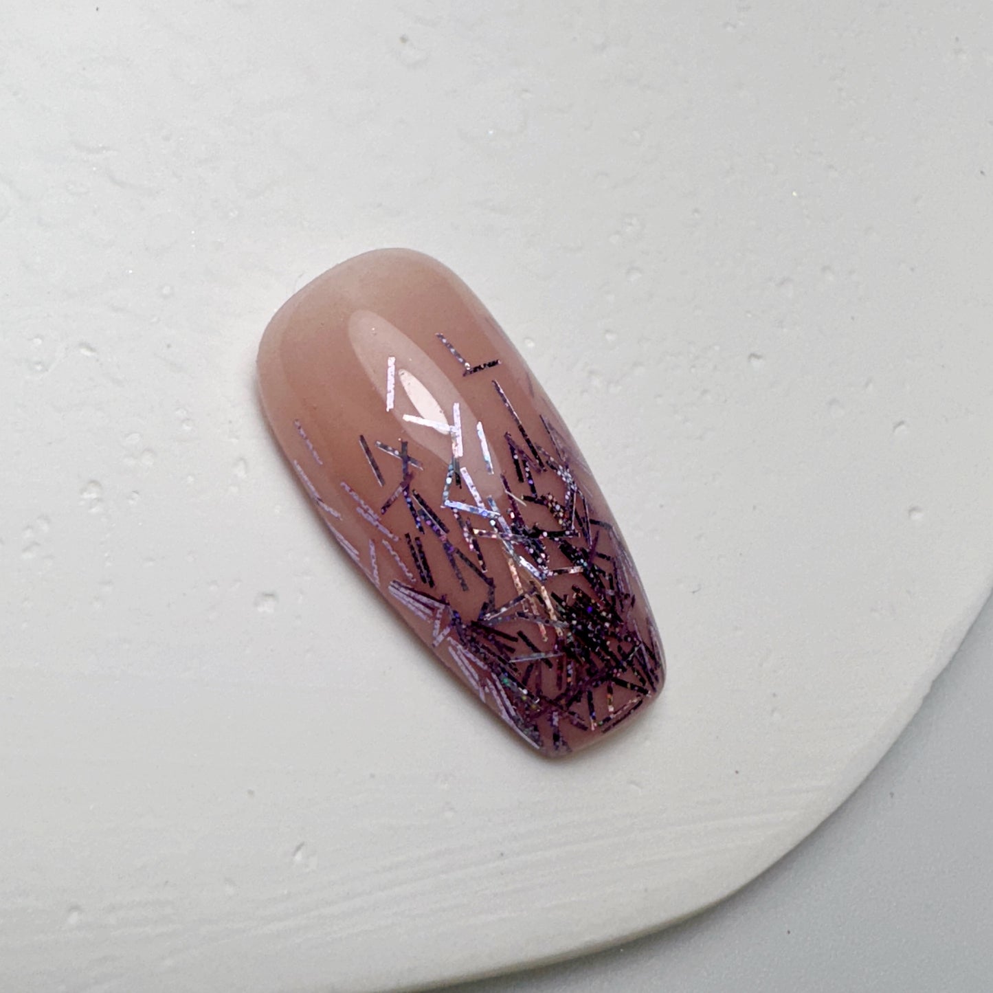 Decorated nail tip on white textured surface.
