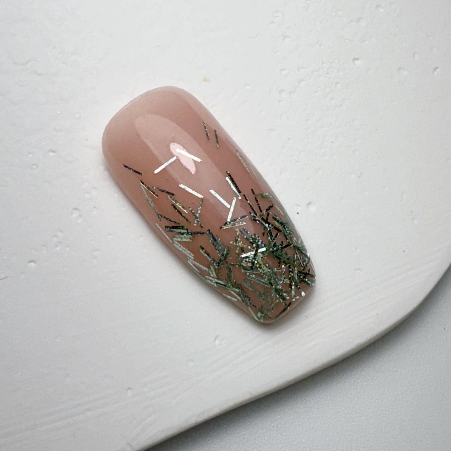 Decorated nail tip on white textured surface.