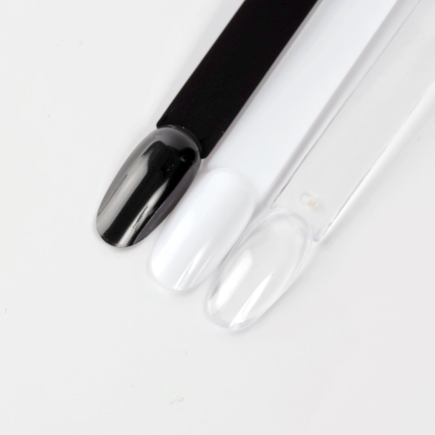 Close up image of black, white and clear oval nail swatcjh sticks on white background.