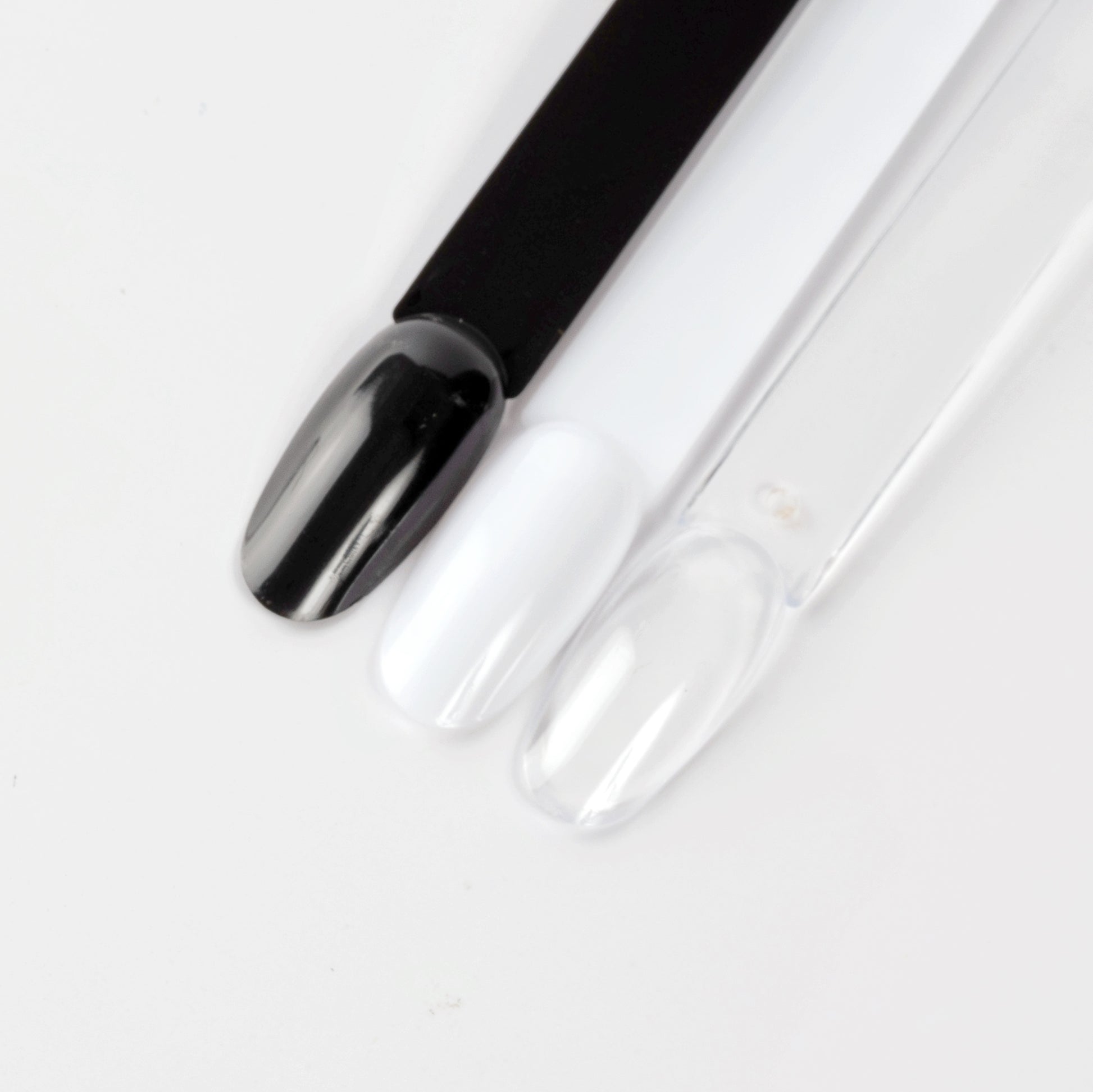 Close up image of black, white and clear oval nail swatcjh sticks on white background.