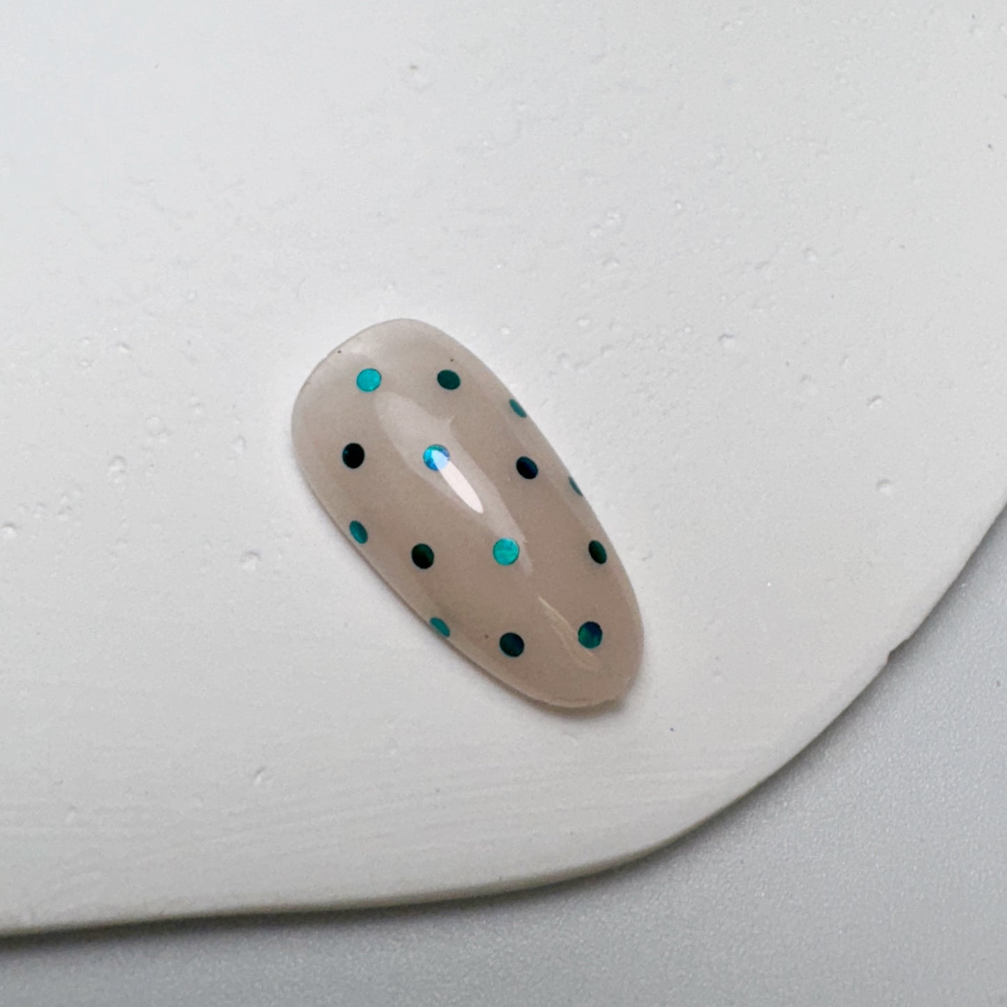 Decorated nail tip on white textured surface.