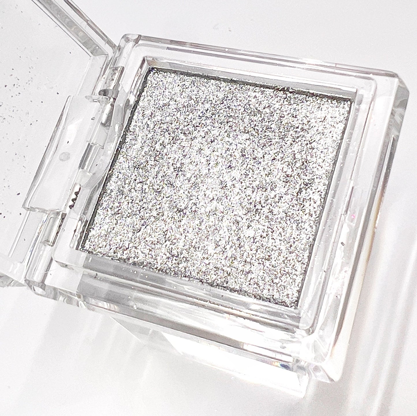 Detail view of compact with metallic powder on white background.