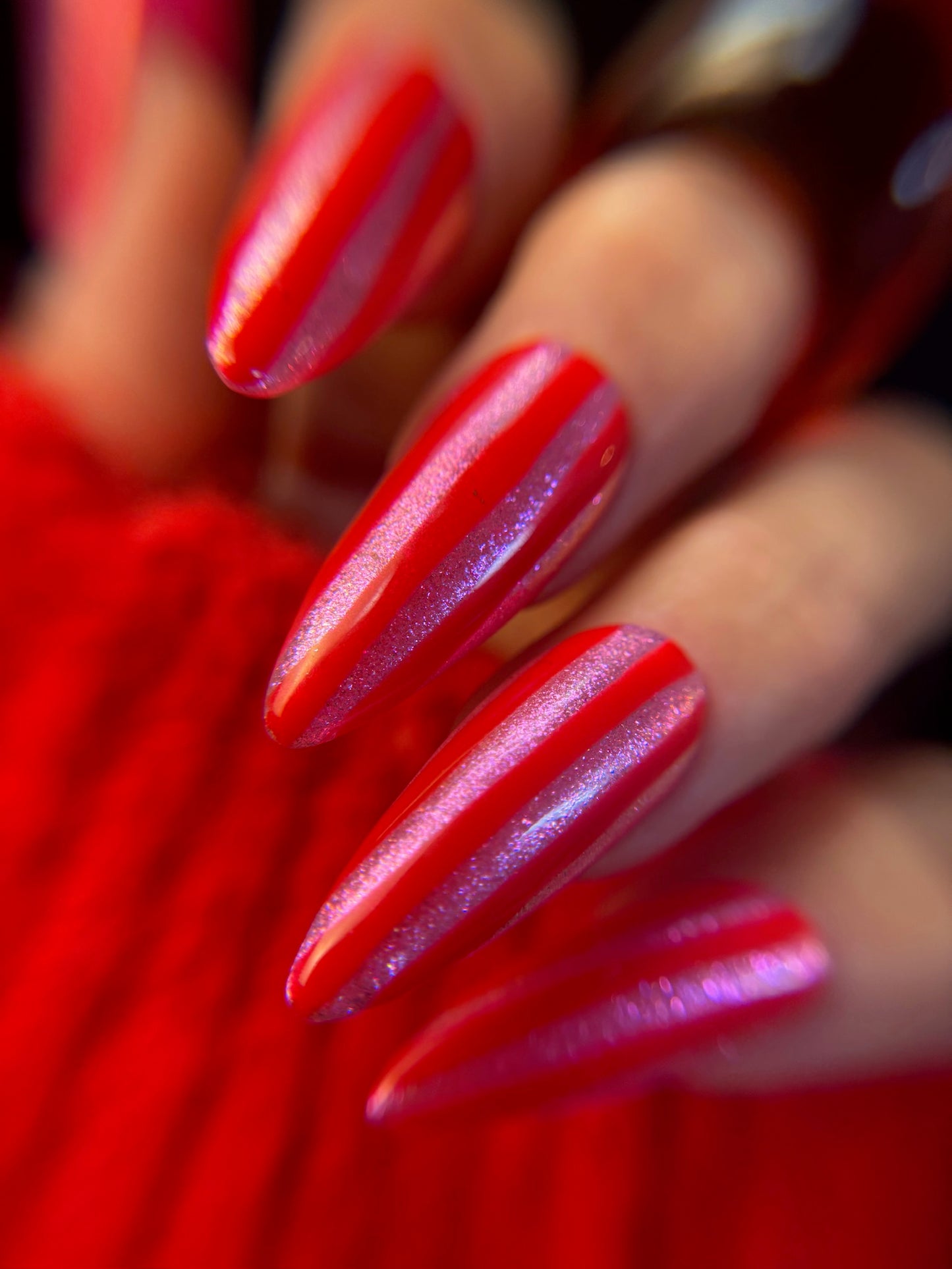 Close-up of a hand with red and pink striped design on a blurred background