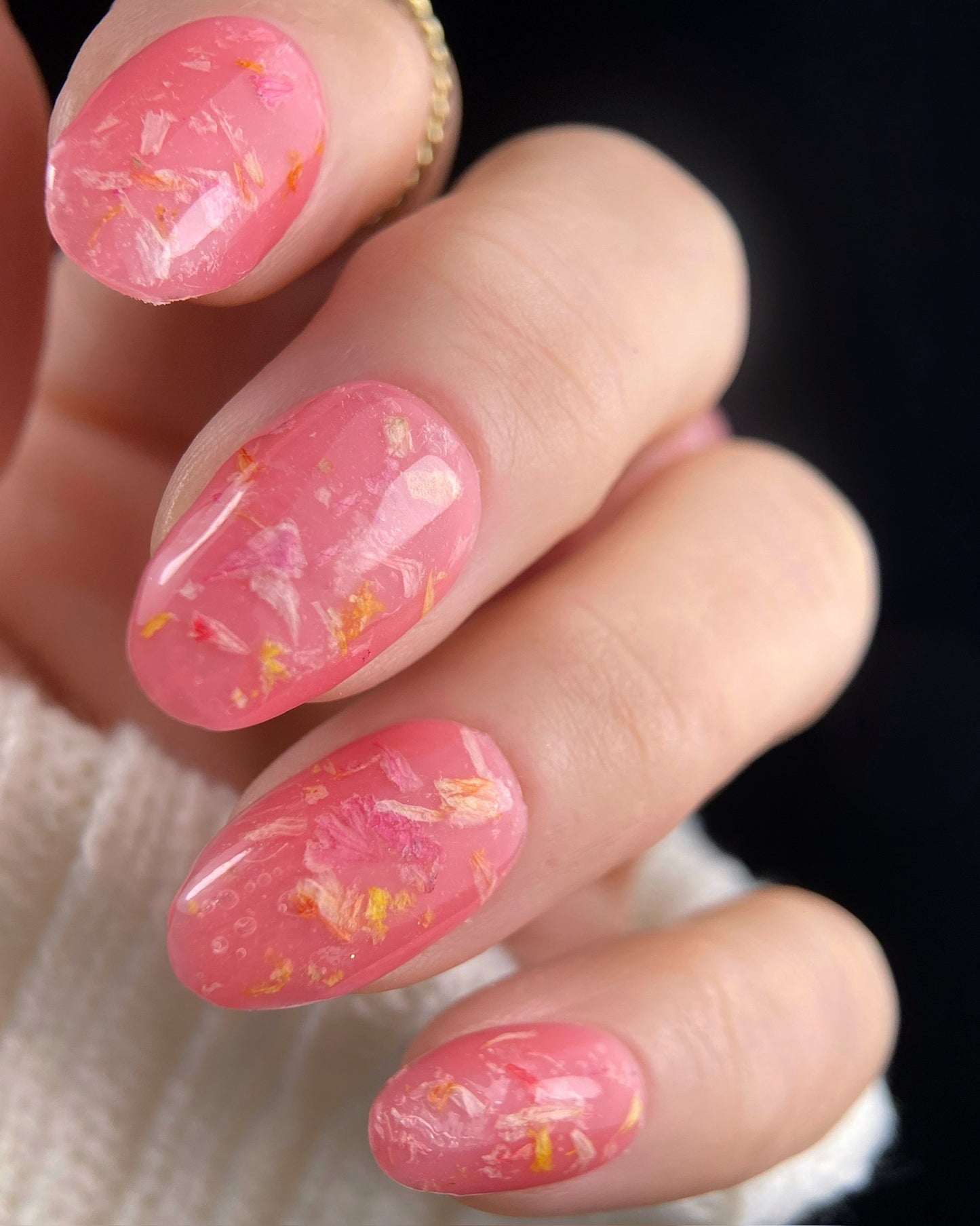 Close-up of a hand with pink nail polish and floral nail art on a blurred background