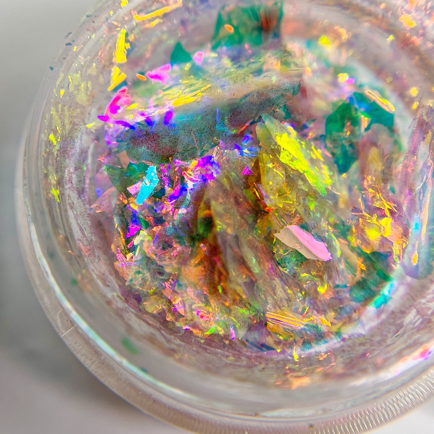 Multicolor flakes in clear jar on white background.