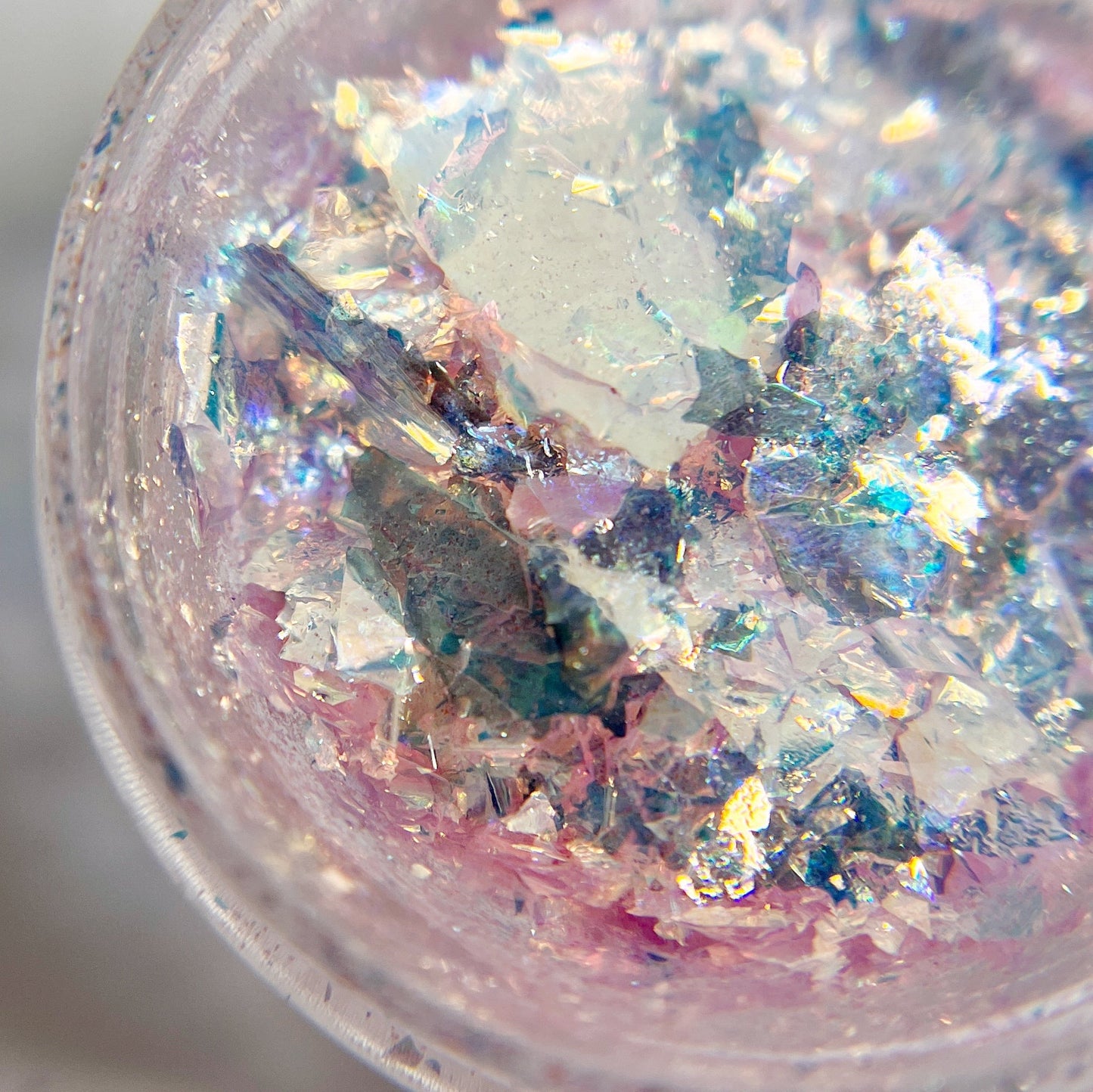 Detailed view of pink ducormatic flakes in clear jar on white background.