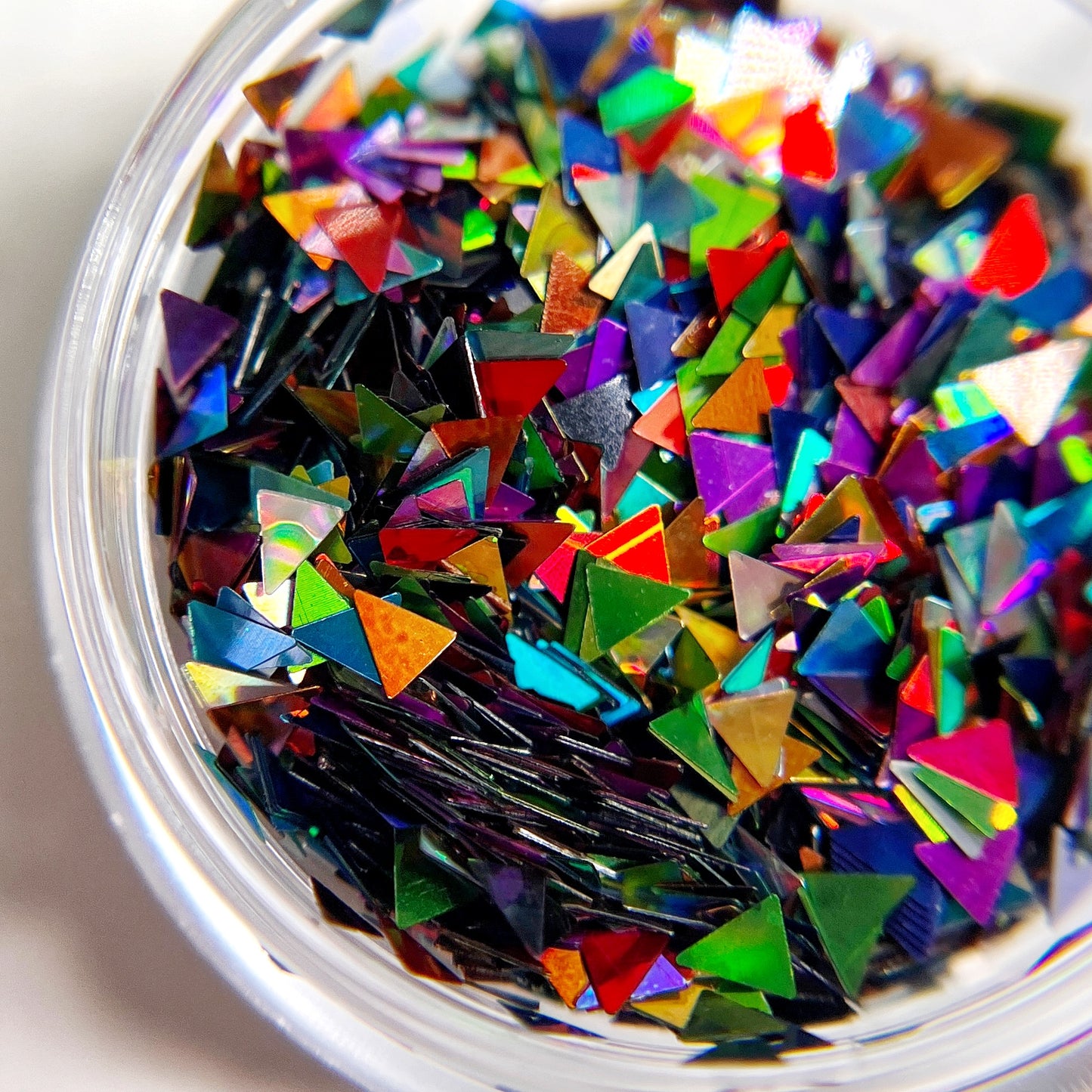 Tiangle shaped glitter mix in clear jar on white background.