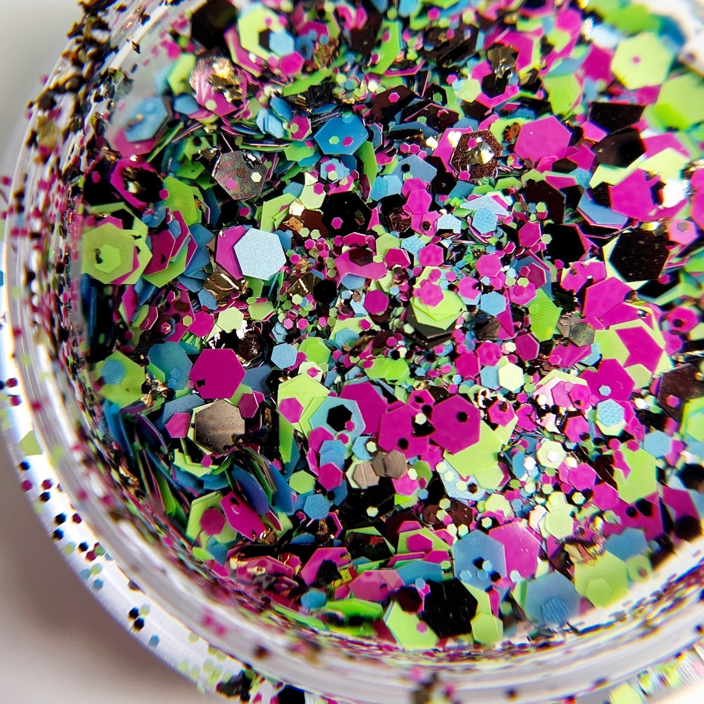 Multi-color and multi-size hexagonal gitte rmix in clear jar on white background.