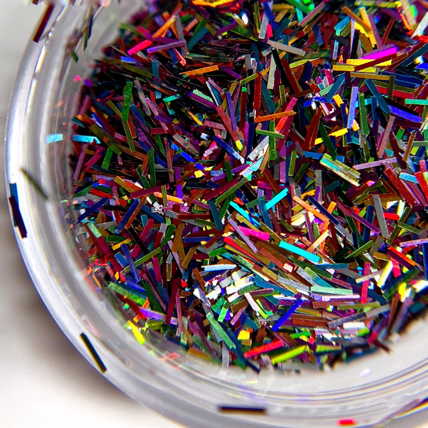 Multicolor tinsel glitter mix in clear jar on white background.