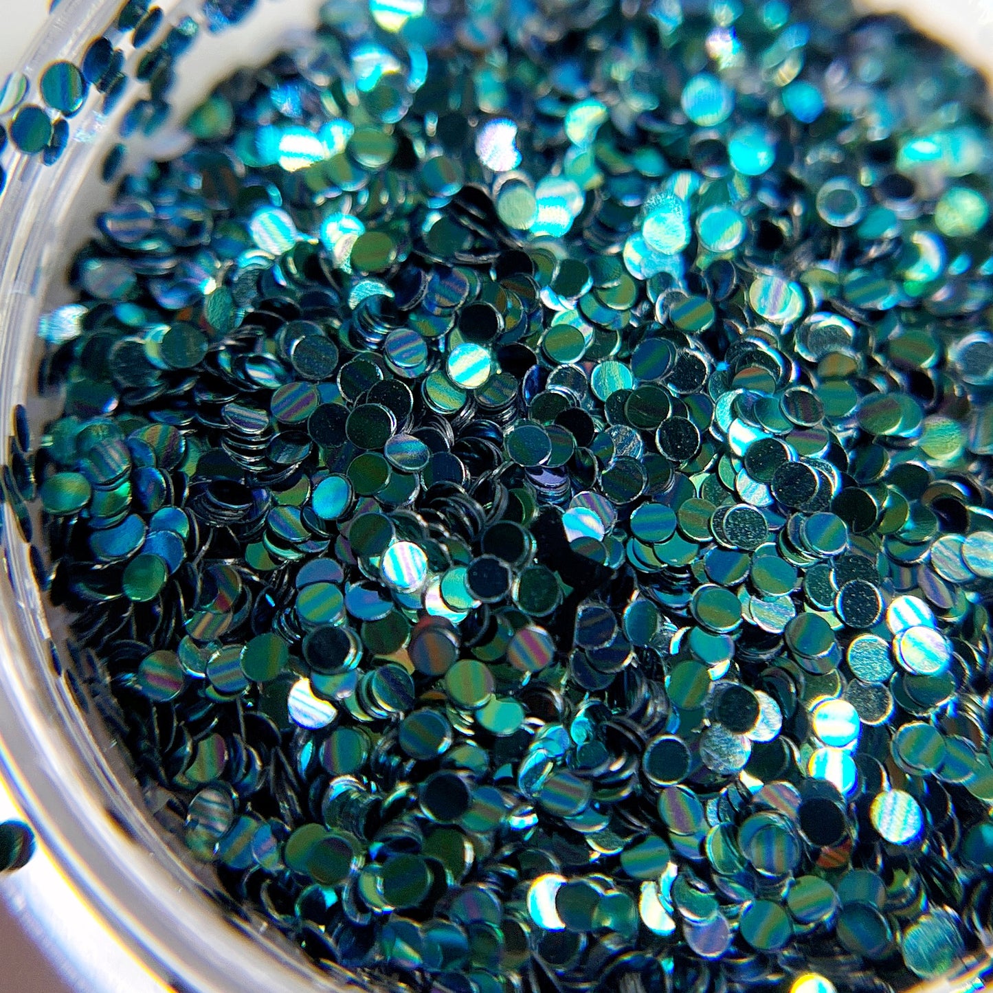Teal circle glitter in clear jar on white background,