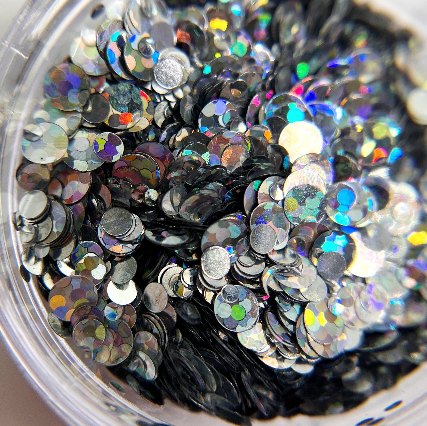 Silver circle glitter in clear jar o nwhite background.
