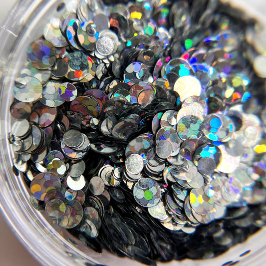 Silver circle glitter in clear jar o nwhite background.