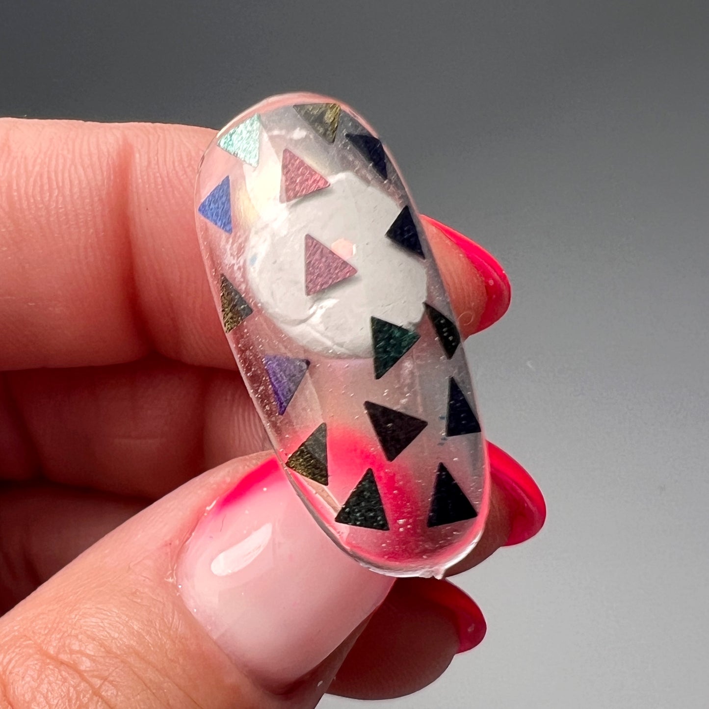 Hand holding decorated nail tip.