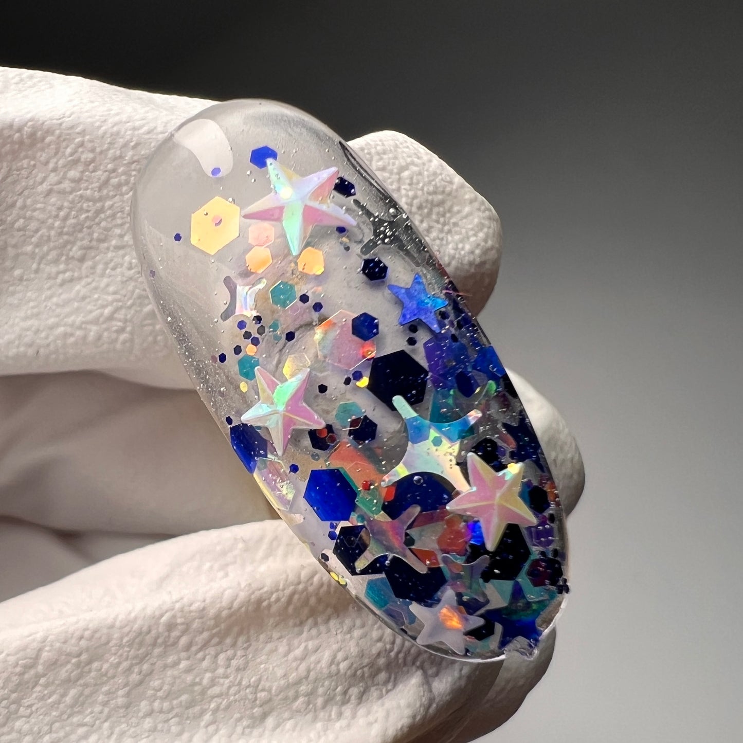 Hand holding decorated nail tip.