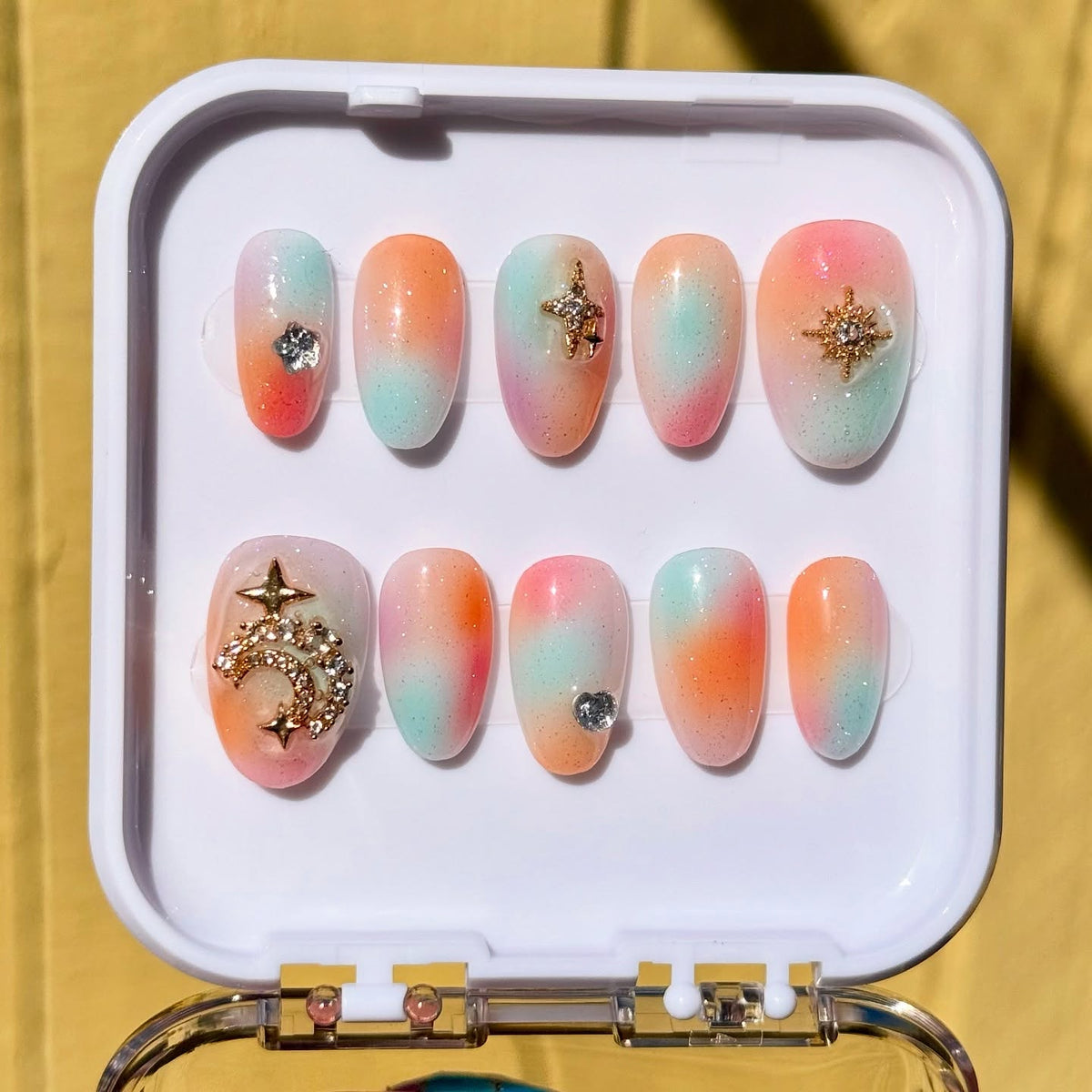 Pastel airbrushed press-on nail set by Melonailz using the Vacation Nail Shop Soft Fade Gradient Palette in Retro Dream, with blended peach, pink and mint tones, fine sparkle and celestial charms.