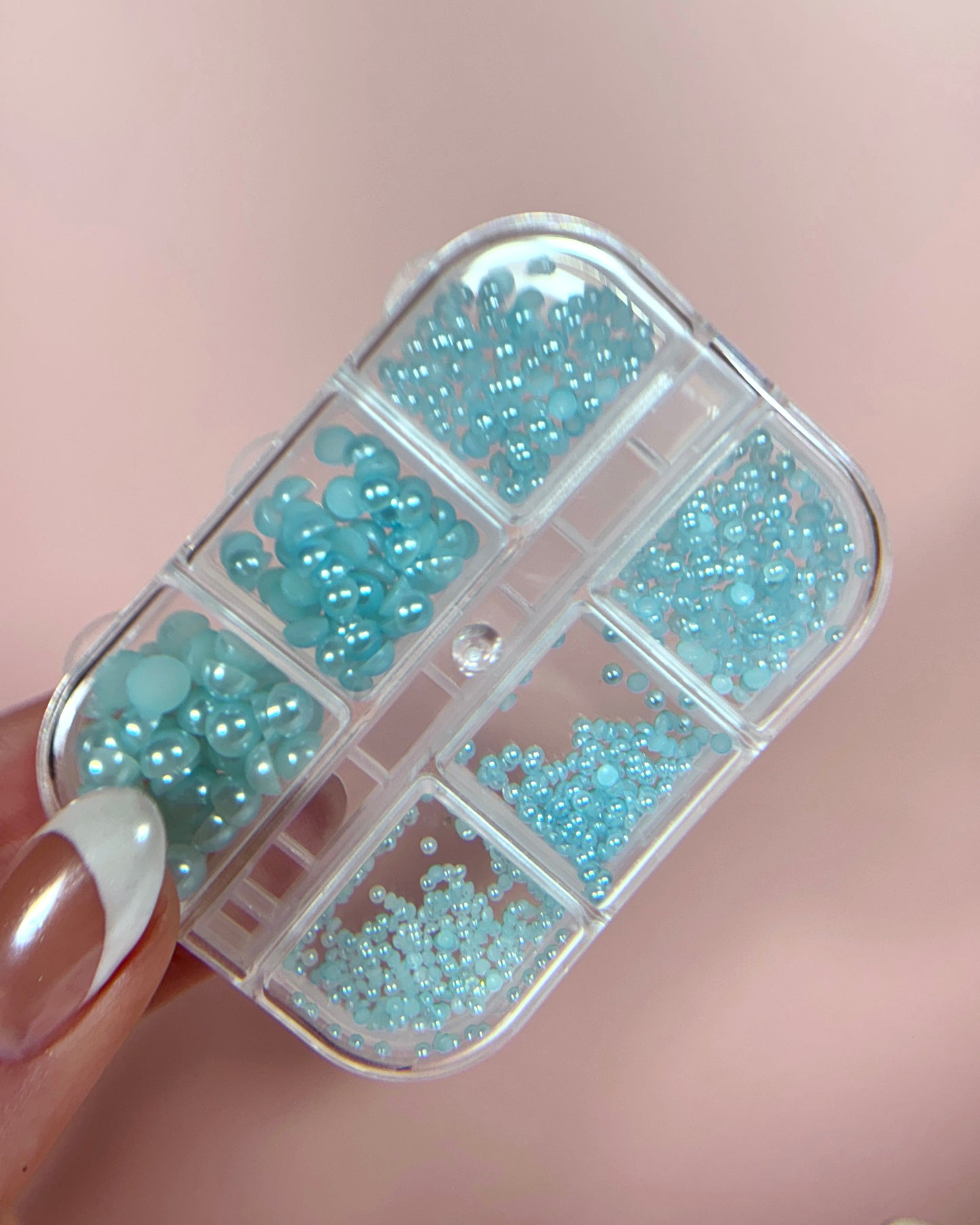 Clear container with blue pearly half-sphere beads on a pink background