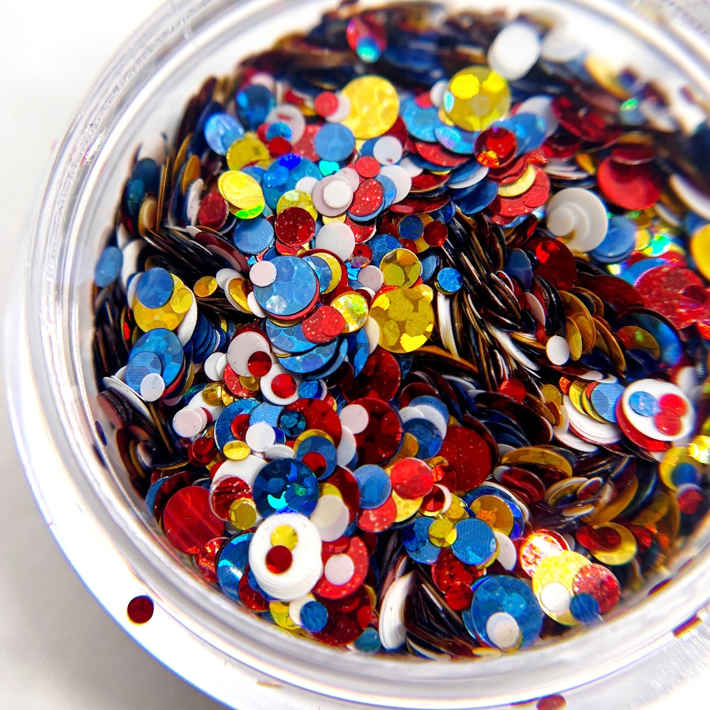 A close-up view of a container filled with multicolored round glitter pieces.