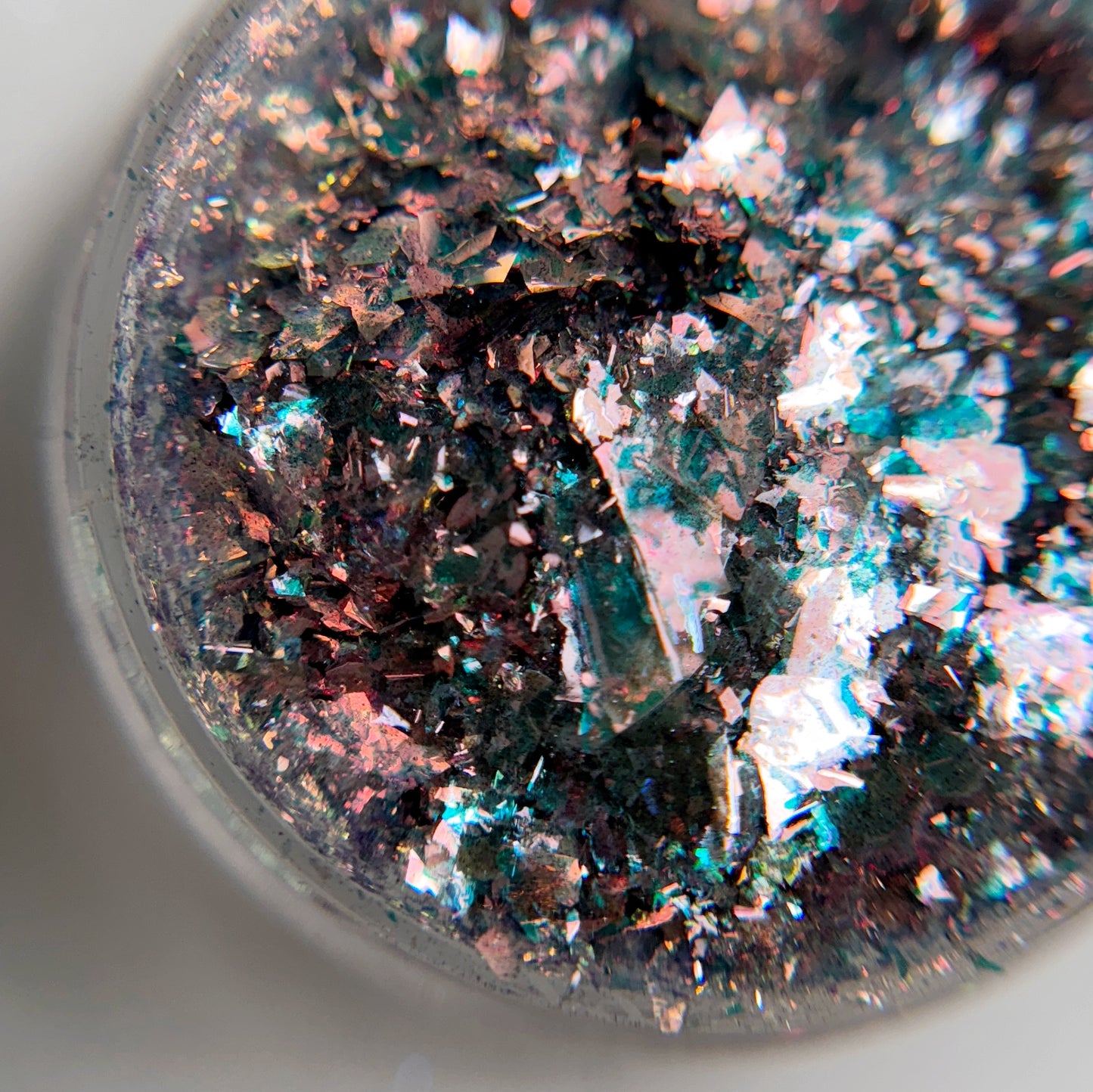 A close-up view of multicolored electric comet flakes in clear jar on blurred background.