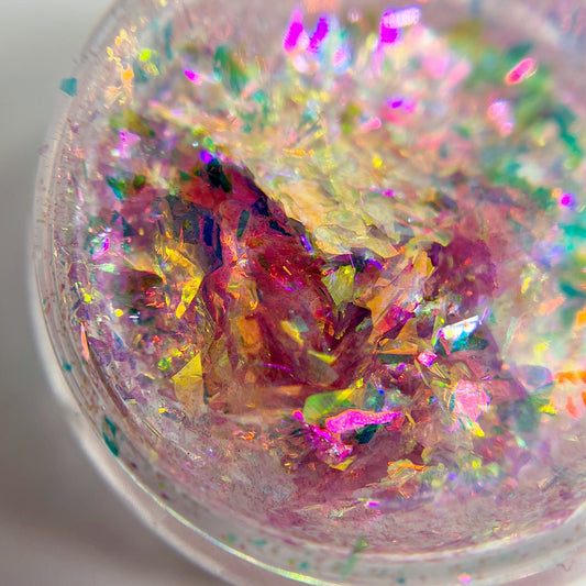 Multicolor flakes in clear jar on white background.