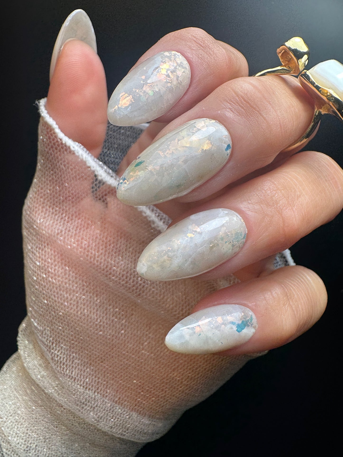 Hand with white marble design and gold ring on a dark background