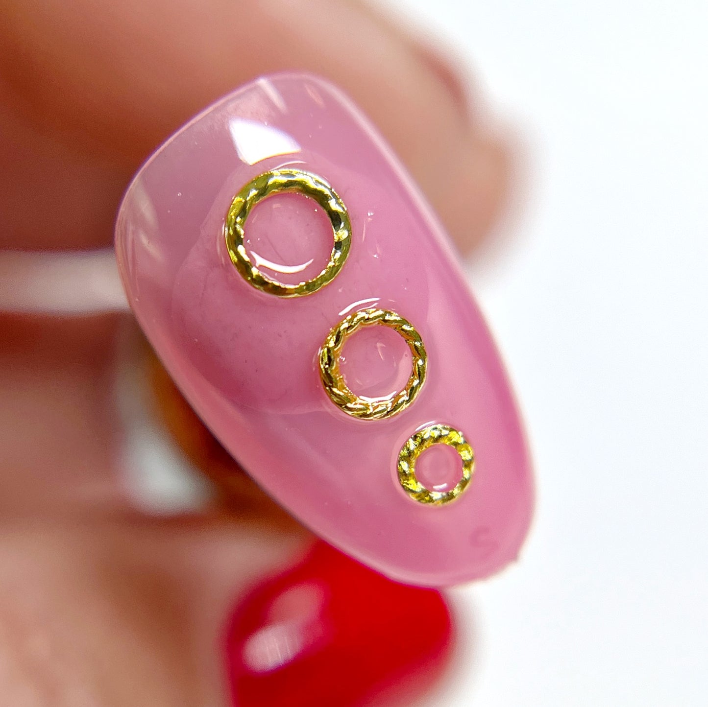 Hand holding decorated nail charm on white background.