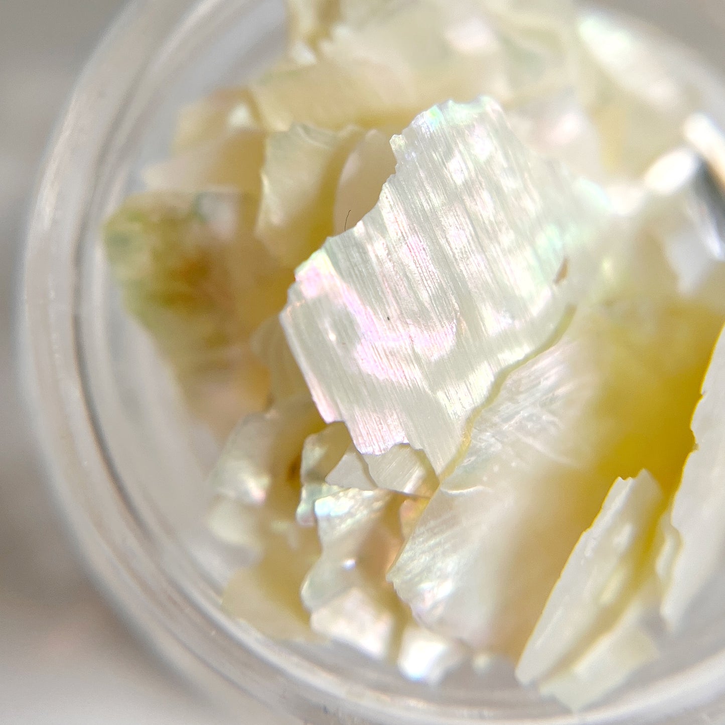 Close up iomage of natural shell flakes in clear jar on white background.
