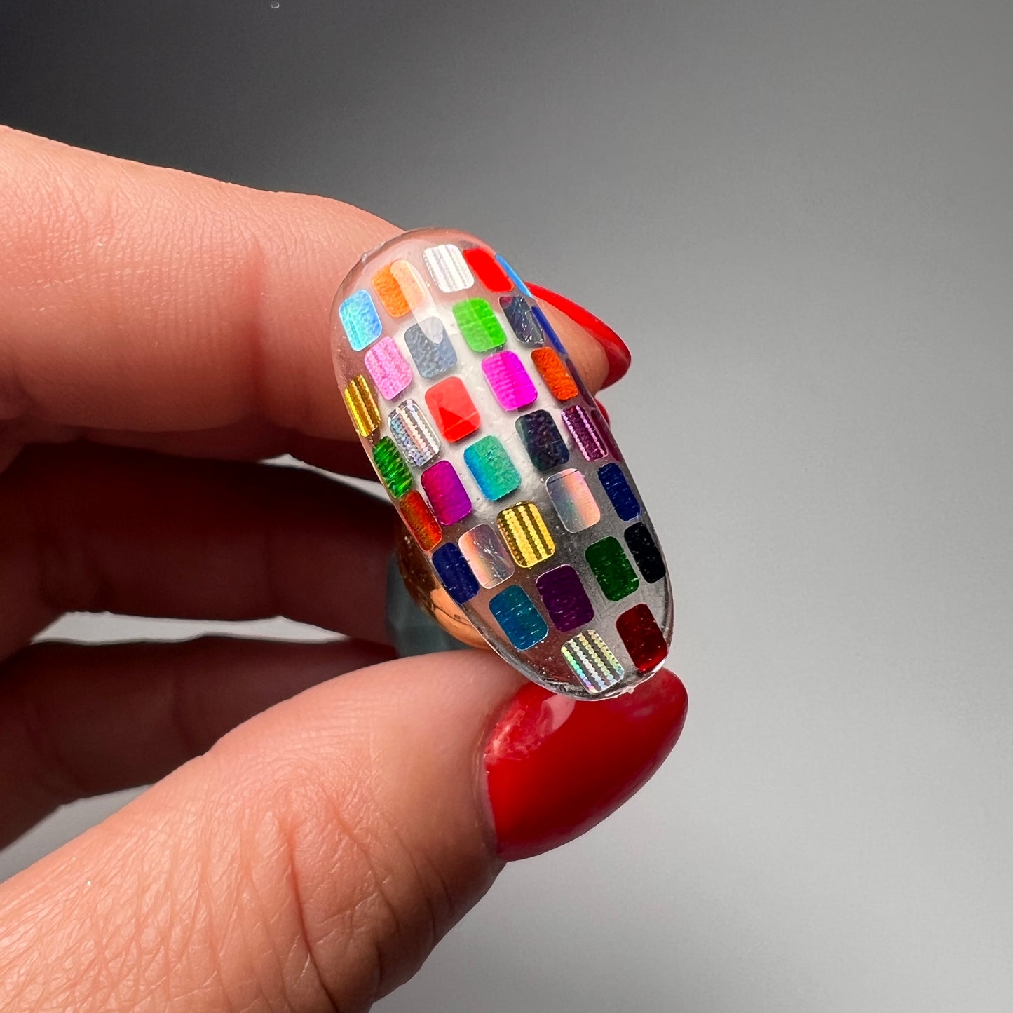 Hand holding decorated nail tip.