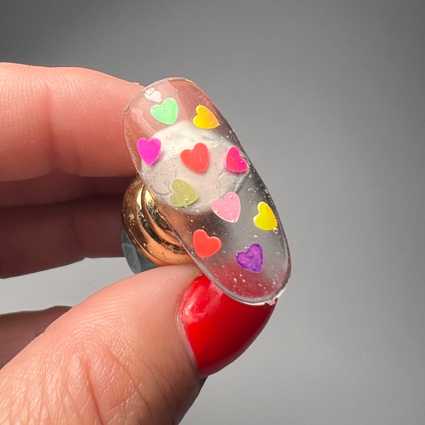 Hand holding nail tip on gray background.