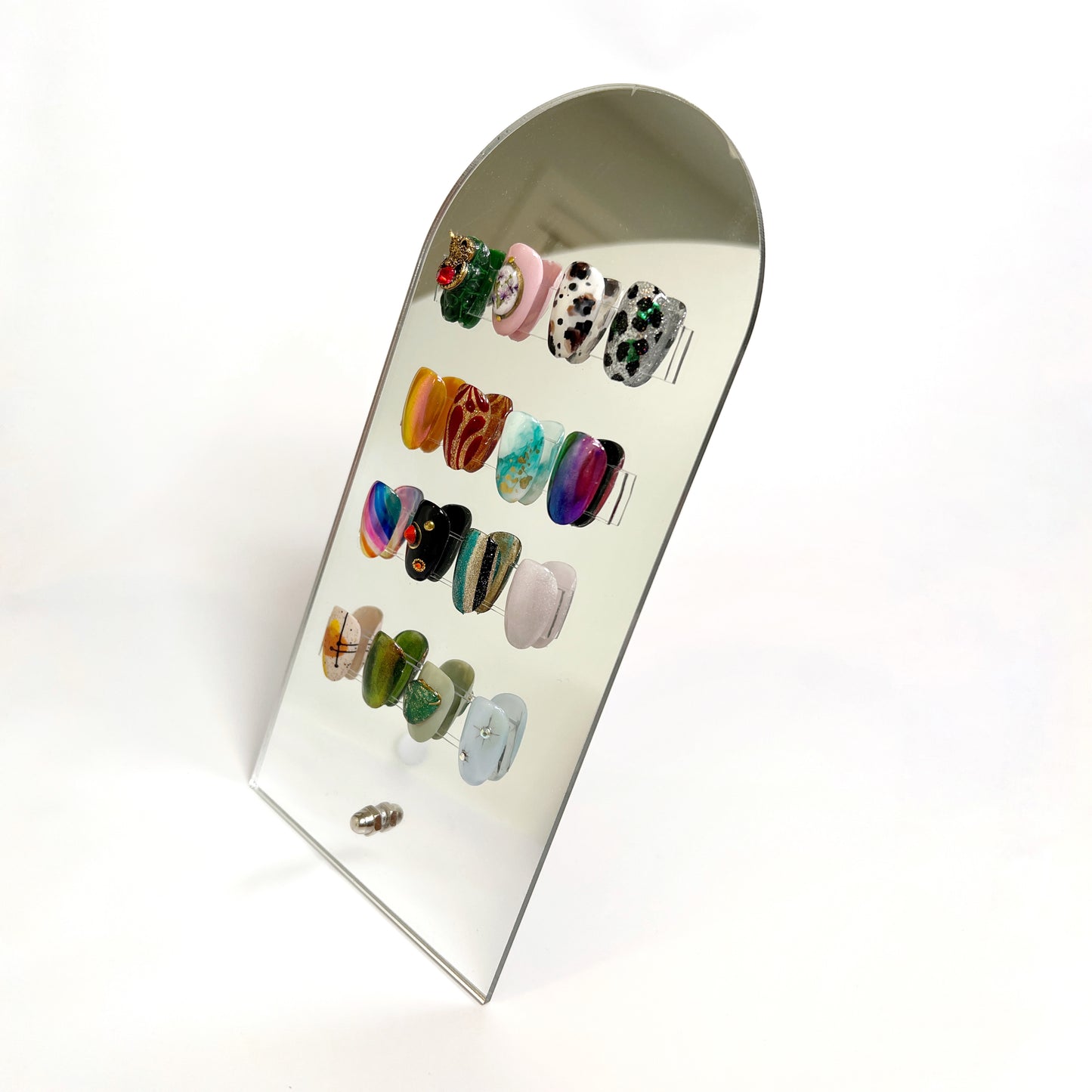 Photo of nail tips on mirrored display on white background.