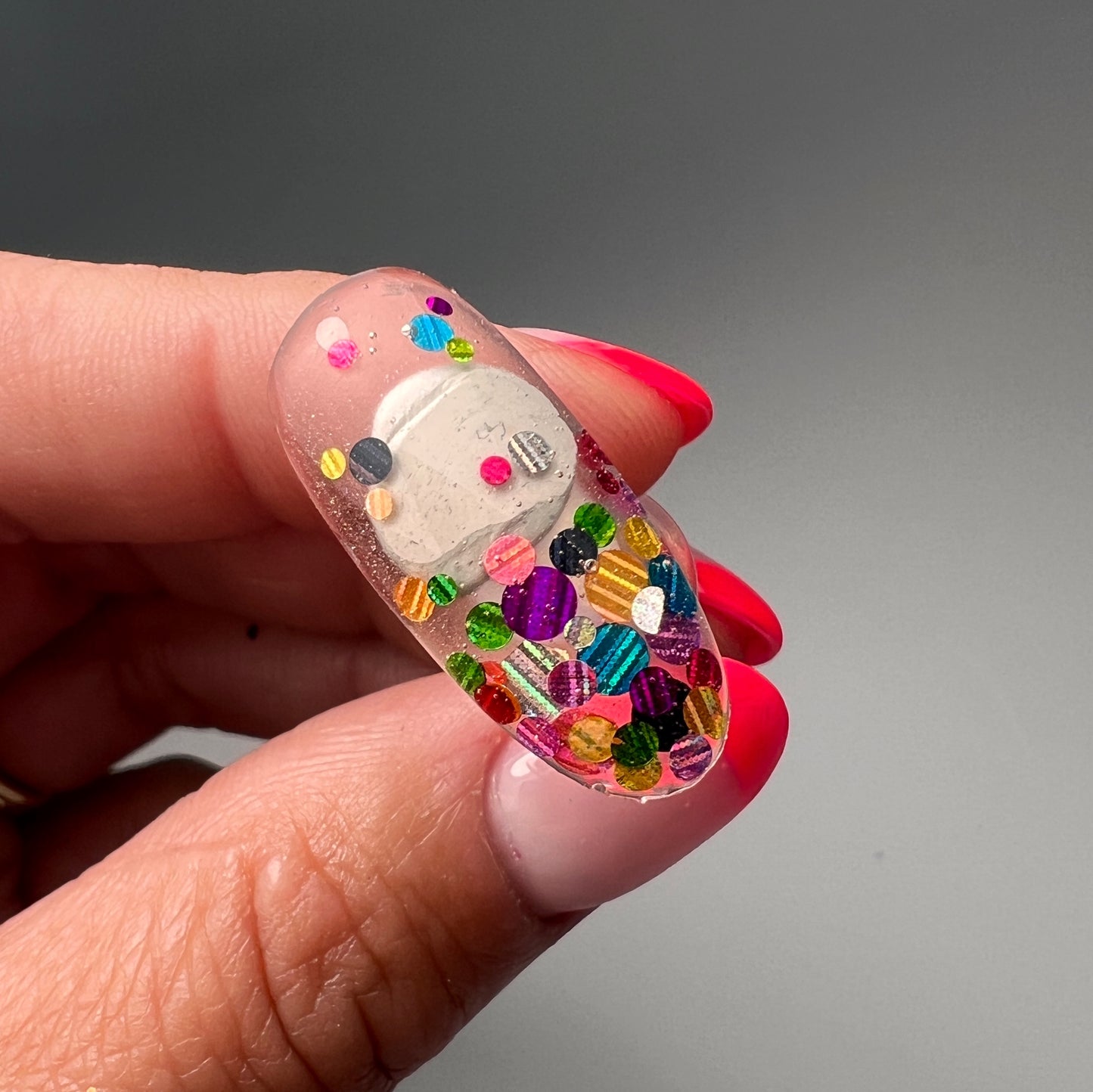 Hand holding gdecorated nail tip.