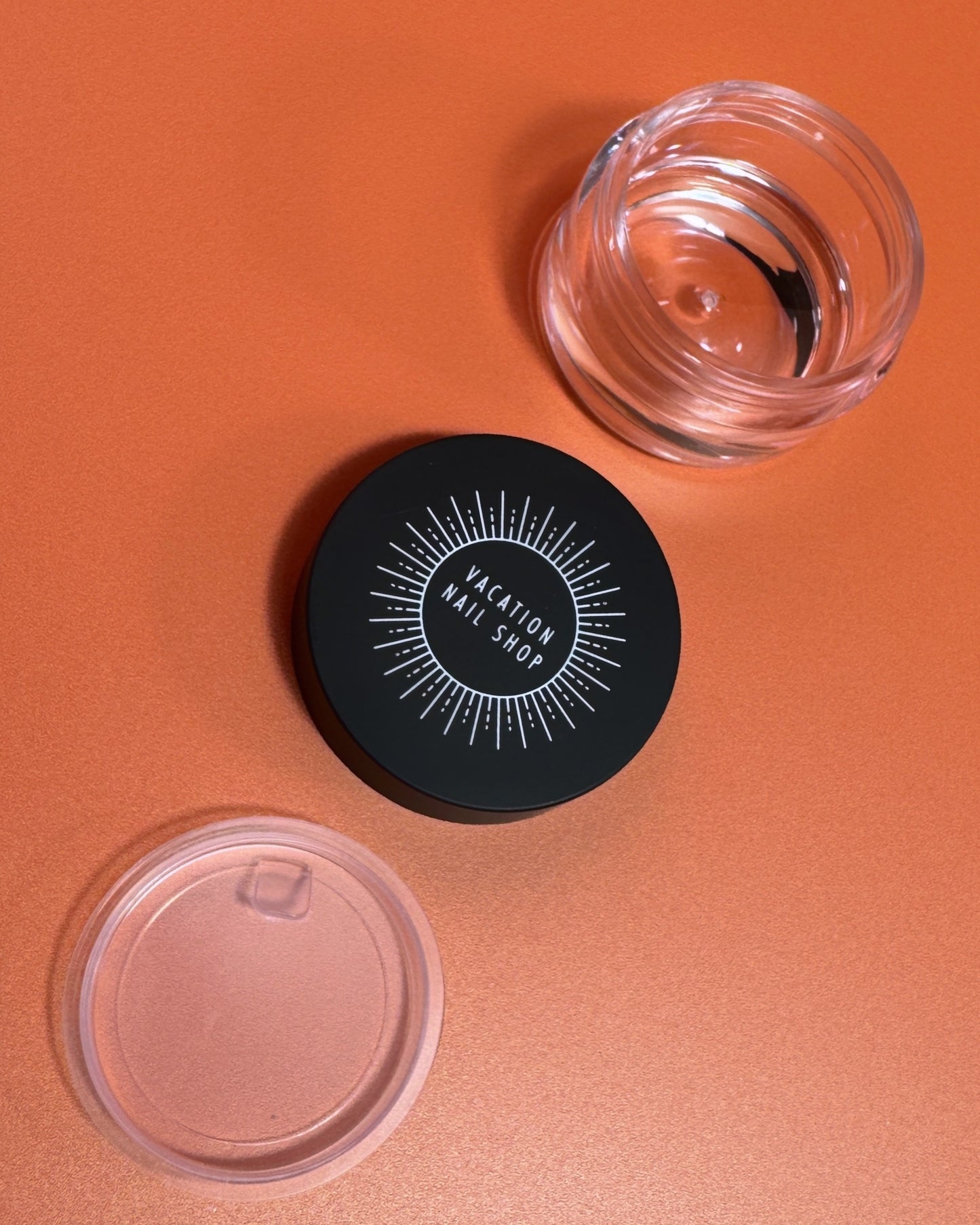 Transparent jar, plastic stopper and black lid on orange background