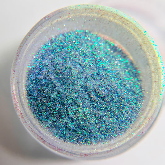 Close up of fine glitter in transparent jar against white background