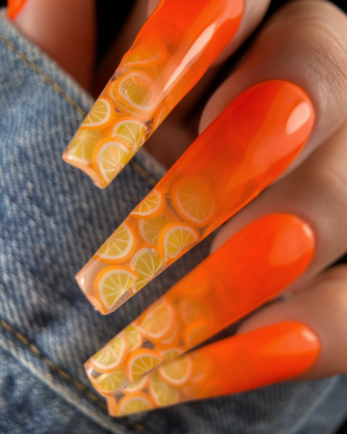 Nails with orange pattern design on a denim background