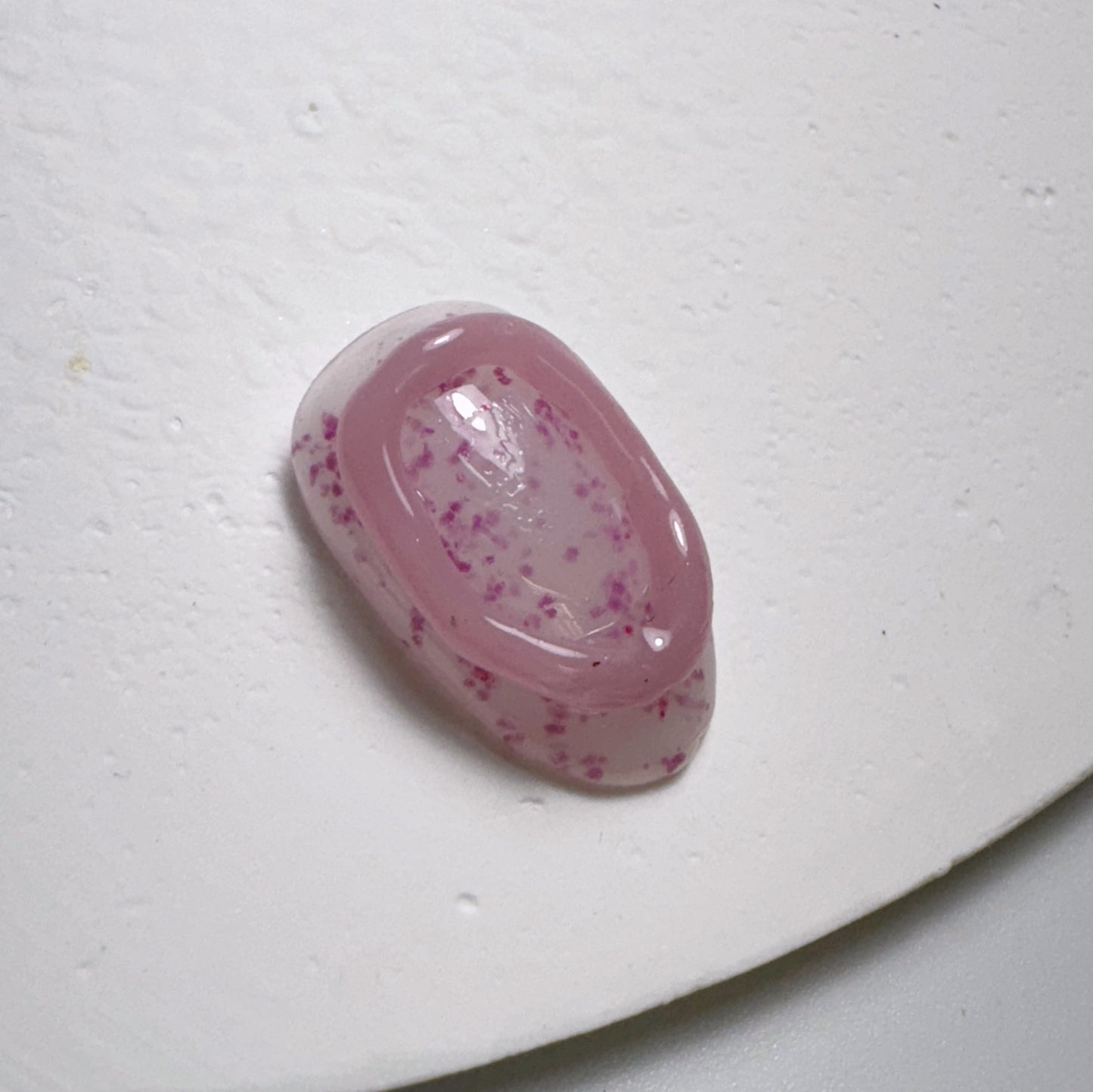 Decorated nail tip on white textured surface.