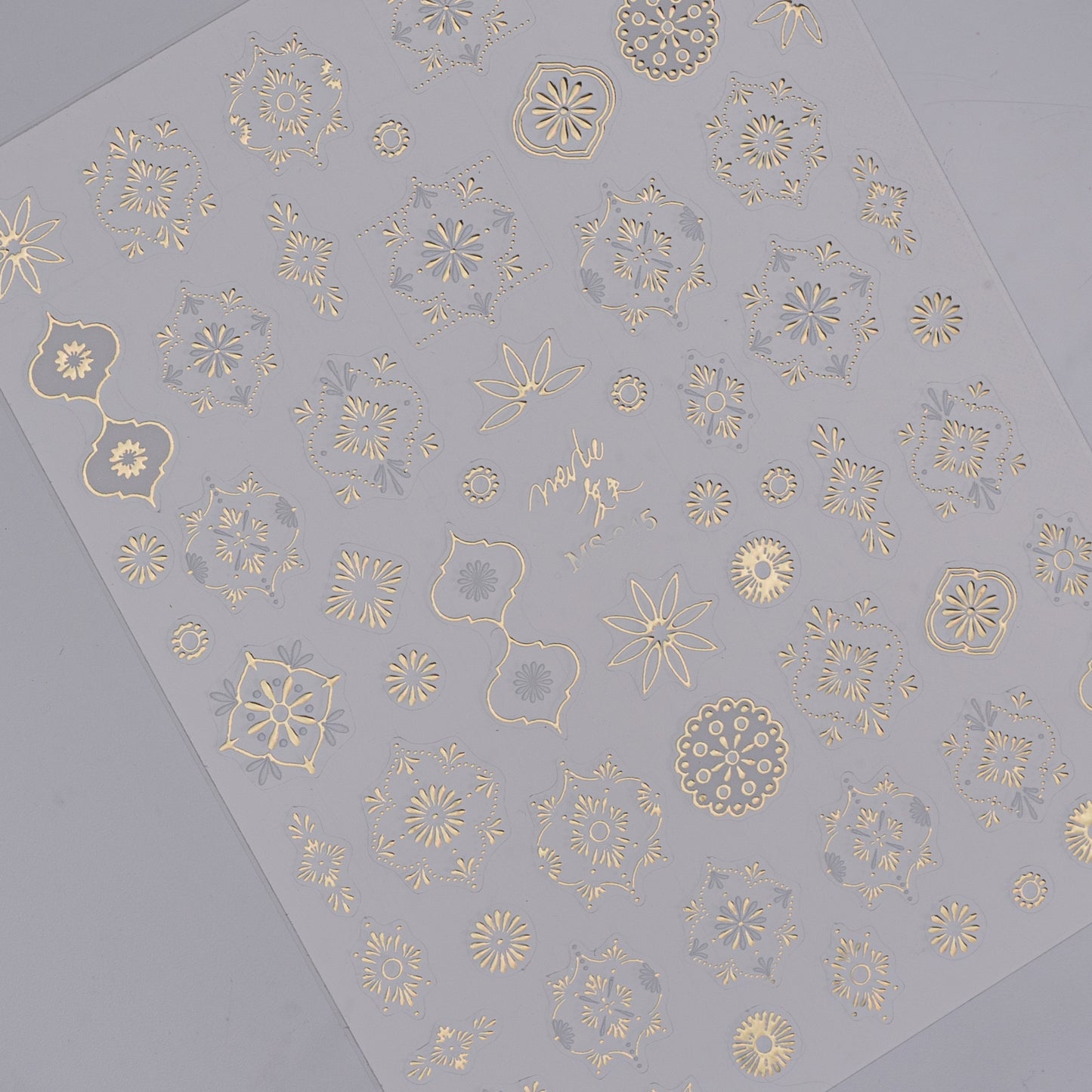 Detail view of gold nail decal sheet on light background.