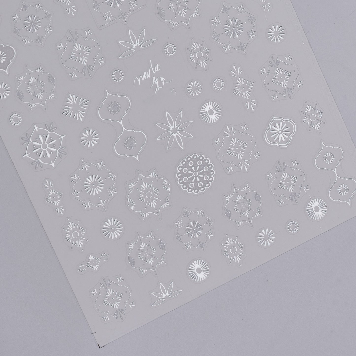 Detail view of silver nail decal sheet on light background.