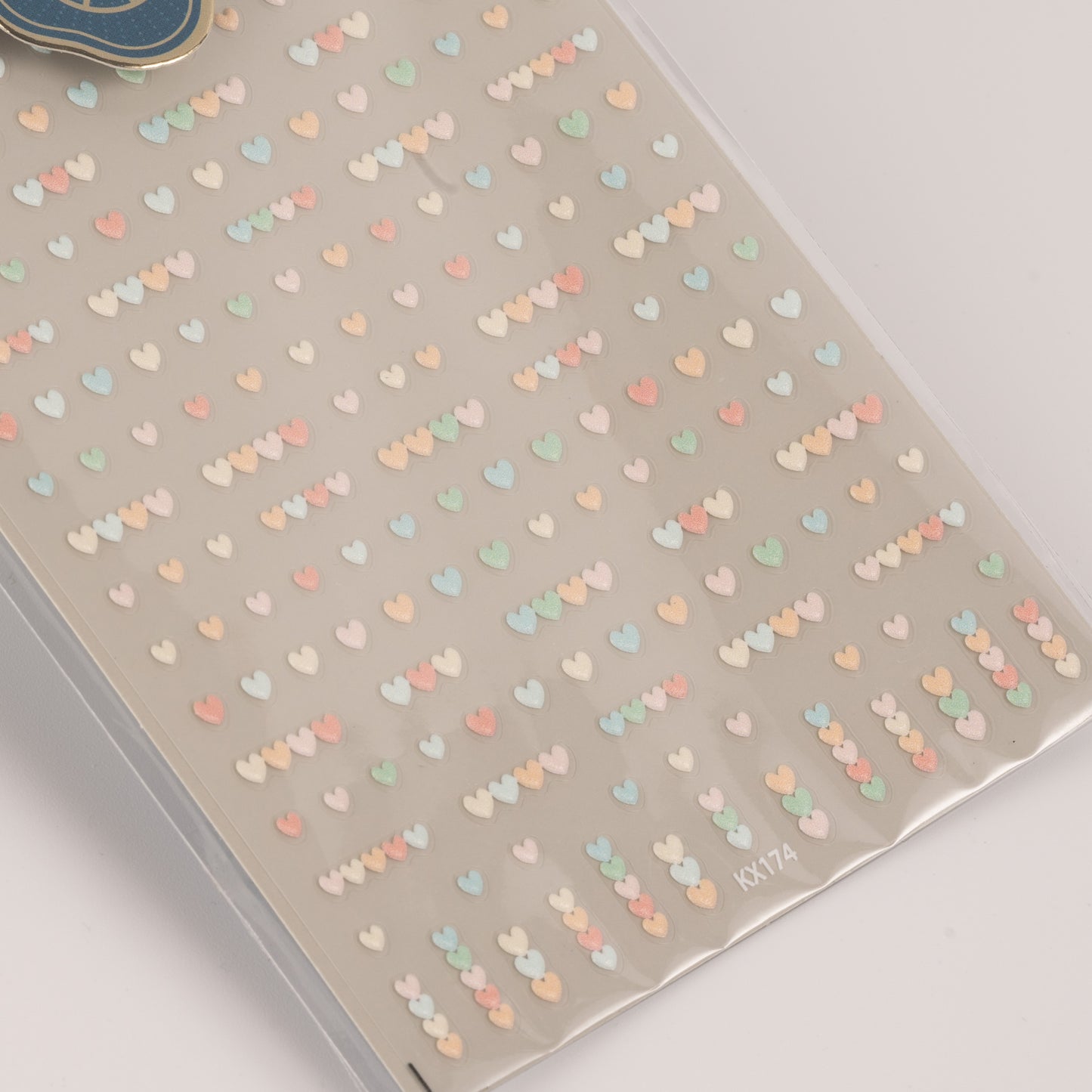 Sheet of small heart-shaped stickers with pastel colors on a gray background