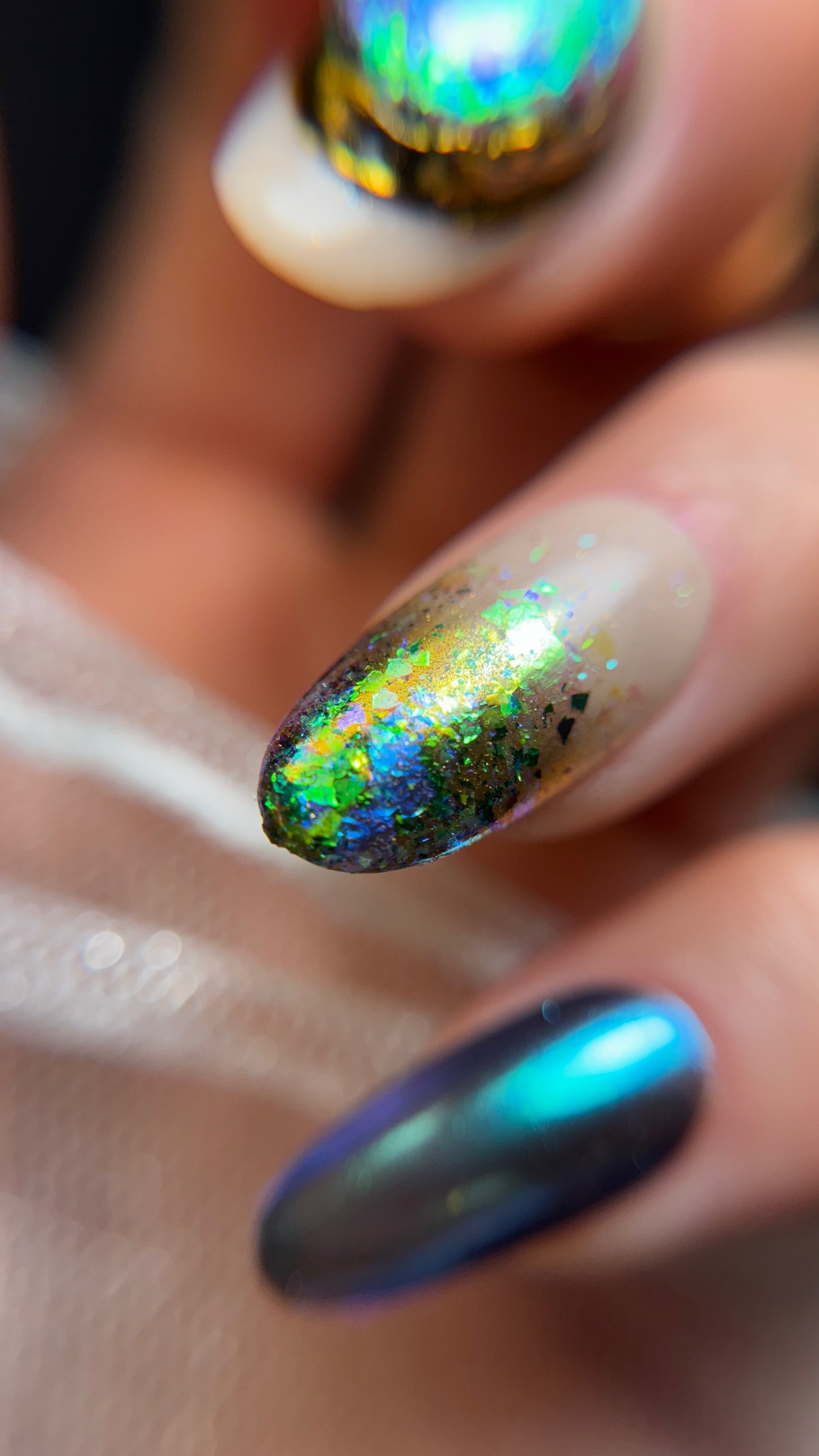 Close-up of a hand with multicolored glittery nail polish on a blurred background