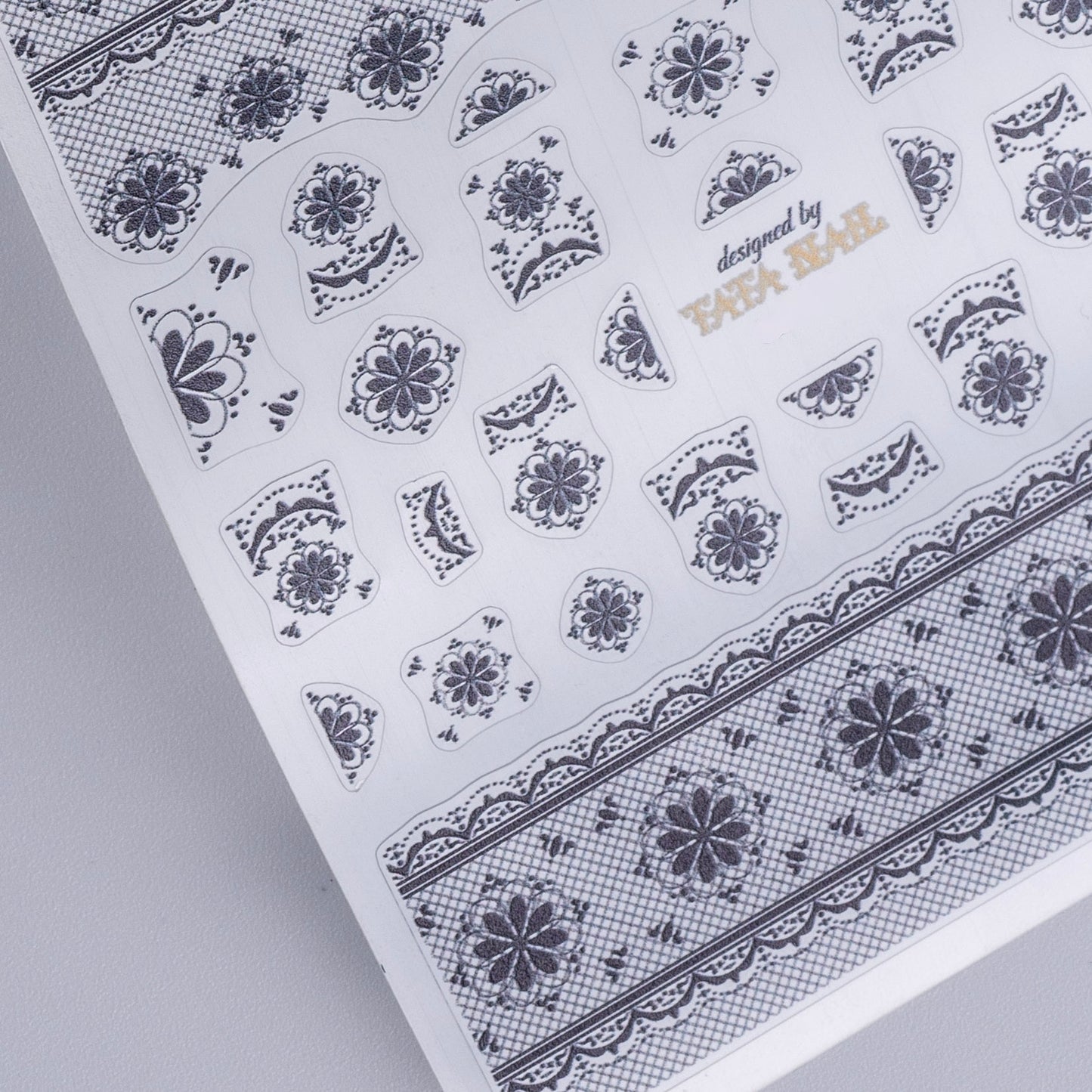 Sheet of floral nail art stickers with 'designed by TATA Nail' text on a gray background