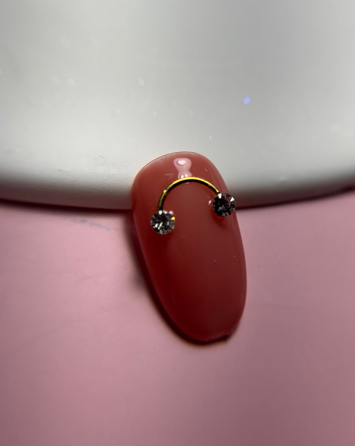 Close up of decorated nail tip on white plate and pink surface
