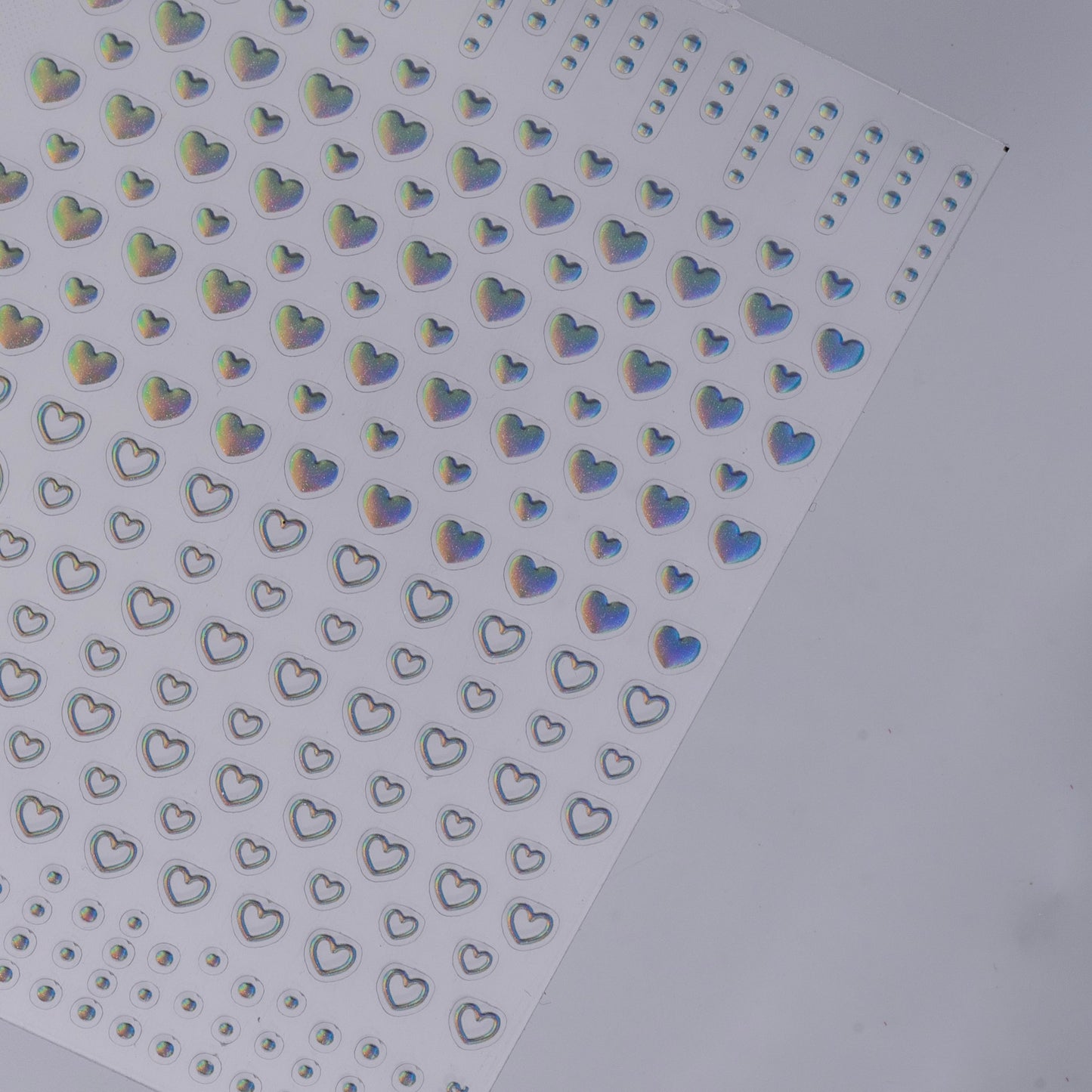 Sheet of holographic heart-shaped stickers on a white background
