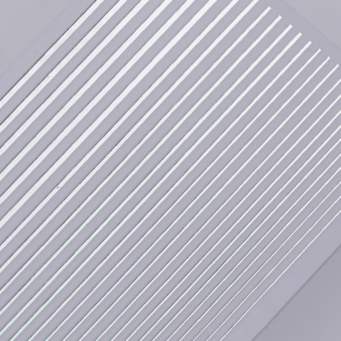 Detail view of silver line nail decal sheet on light background.