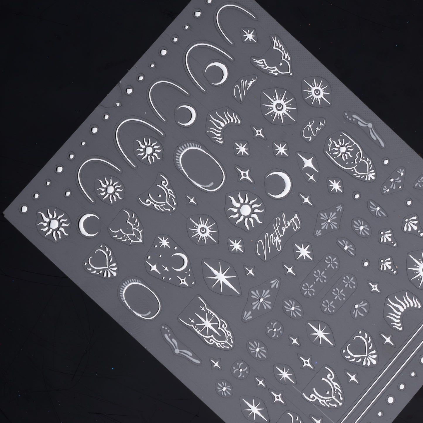 Detail view of nail decal sheet on dark background.