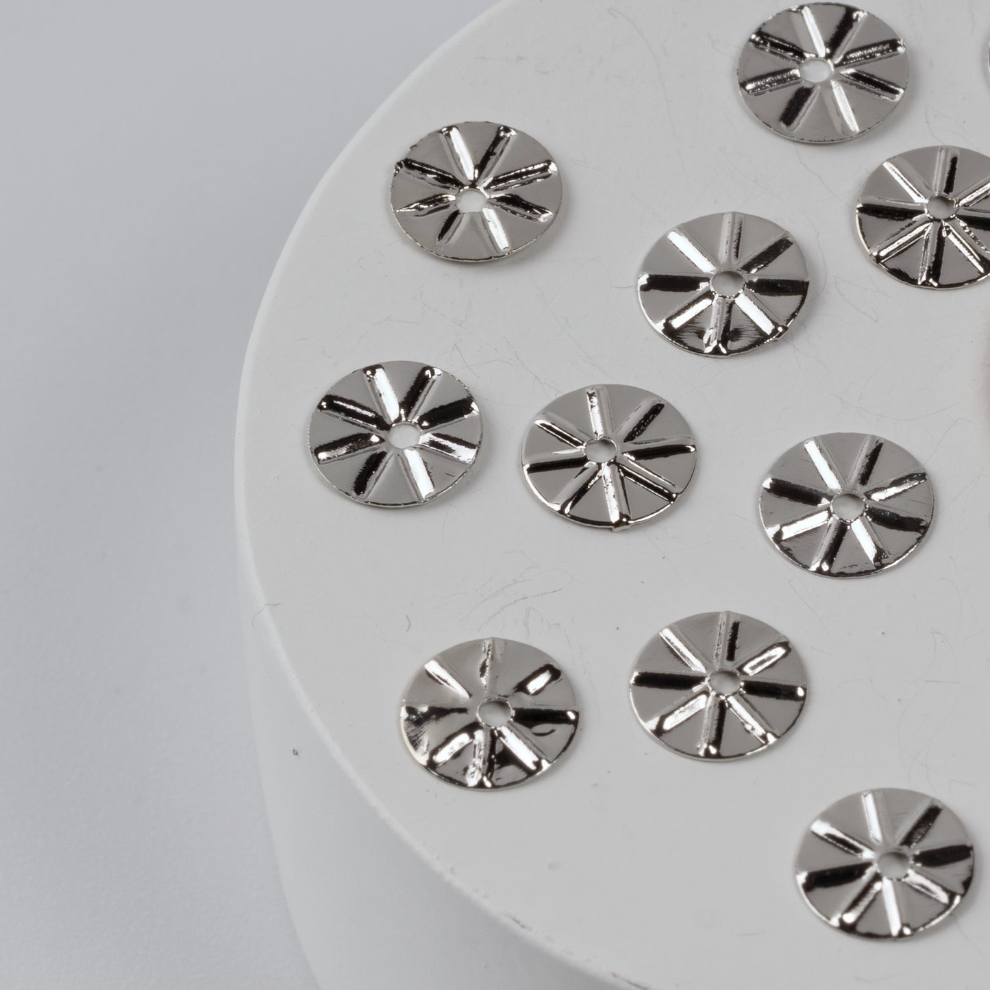 Silver circular embellishments on a white round base