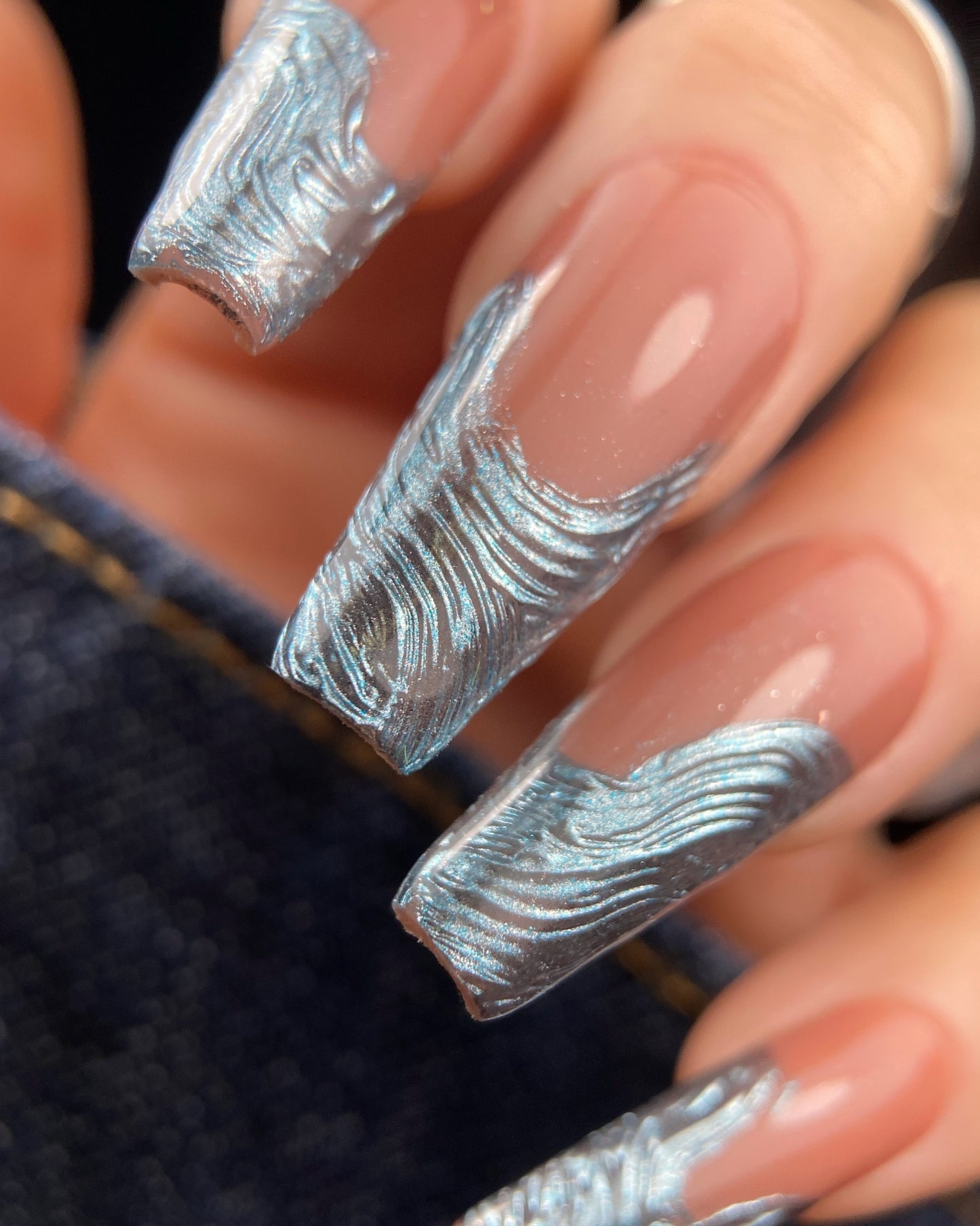 Close-up of nails with blue textured design on a dark background