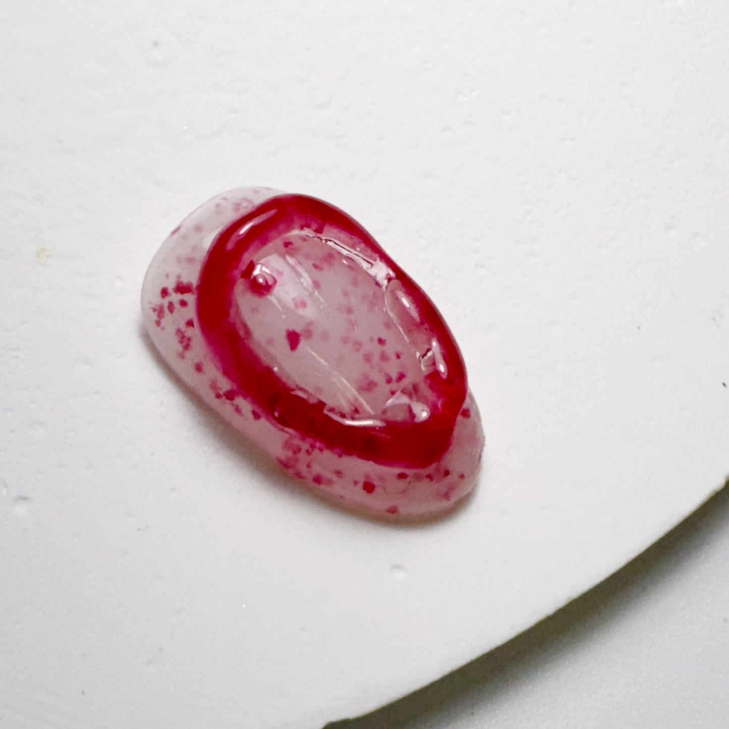 Decorated nail tip on white textured surface.