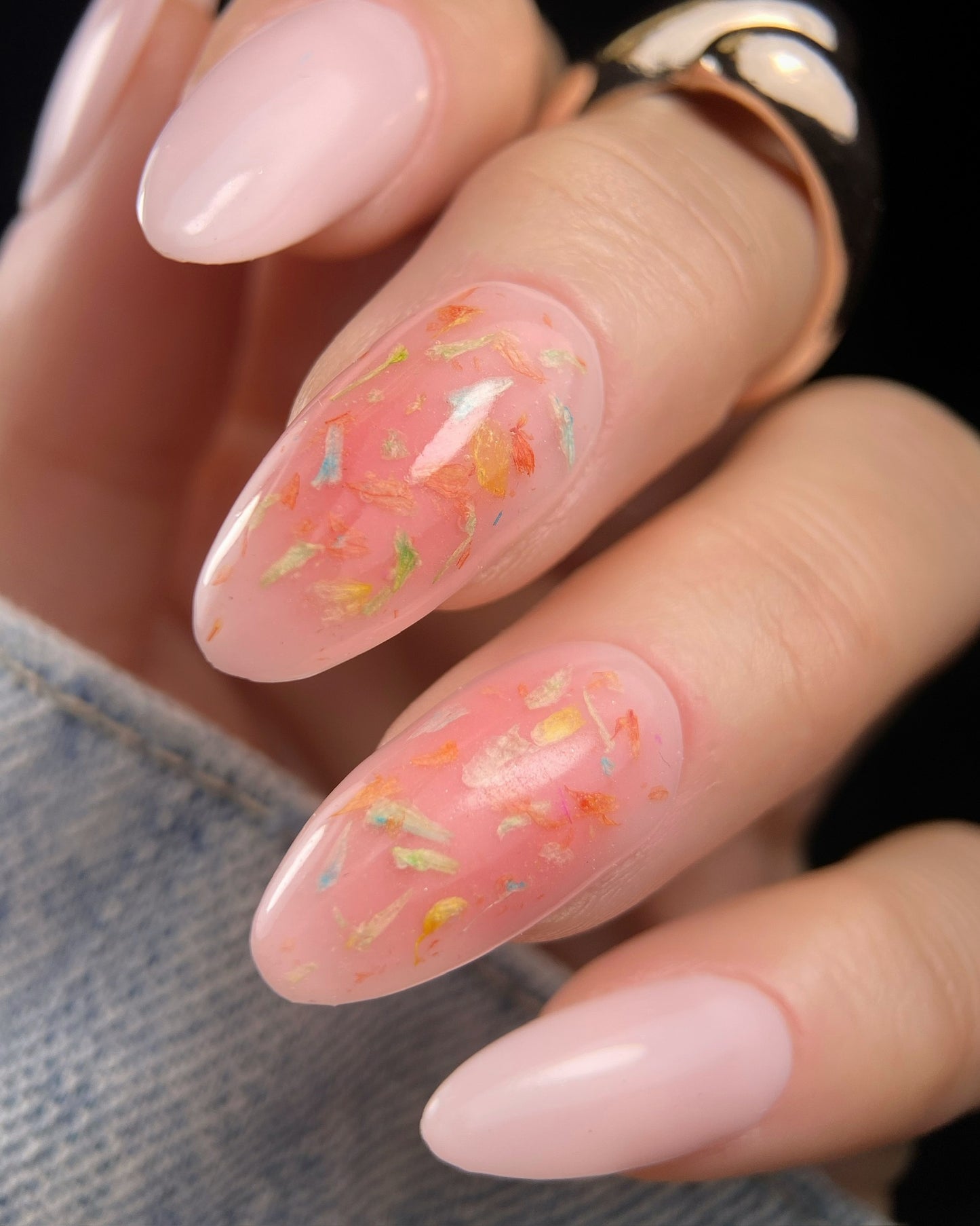 Close-up of a hand with pink nail polish and floral designs.