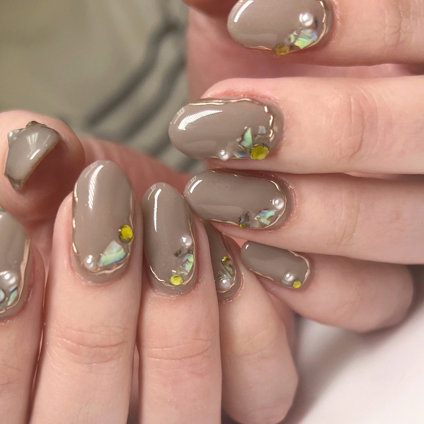 Picture of hands with nail art featuring shell flakes.