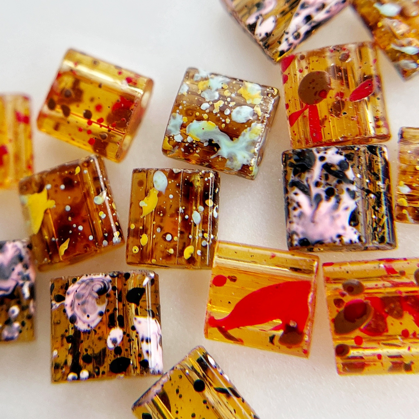 Multicolor square resin nail charms on white background.
