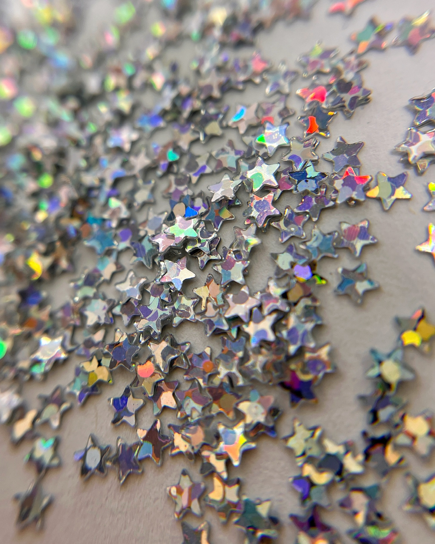 Silver star glitter scattered on white background.